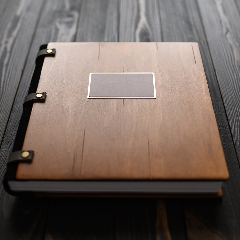 an-old-photo-album-with-a-wooden-cover-and-a-shiel-54LW5CU.jpeg